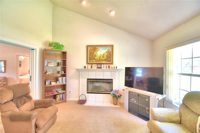 living room with light carpet, high vaulted ceiling, and a tiled fireplace