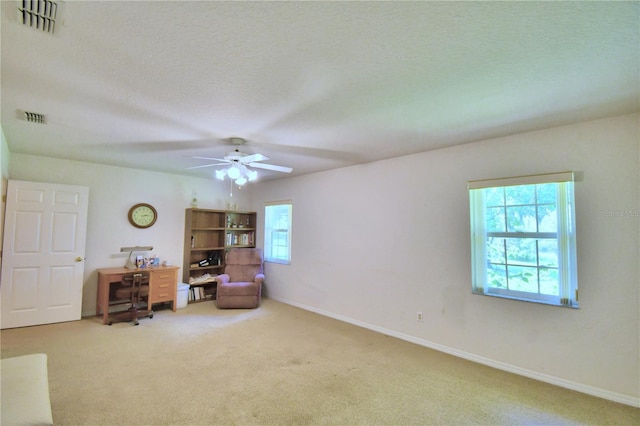 interior space featuring ceiling fan, a textured ceiling, and light carpet