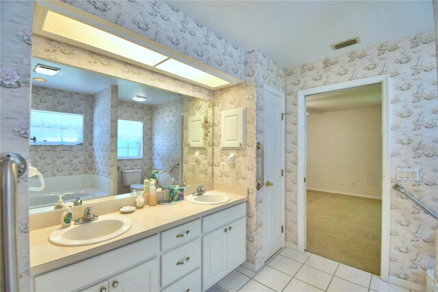 bathroom featuring a bath, tile patterned floors, and dual bowl vanity