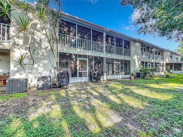 back of house with central AC and a lawn