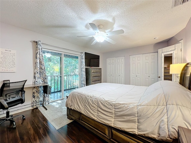 bedroom featuring access to outside, two closets, ceiling fan, dark hardwood / wood-style floors, and a textured ceiling