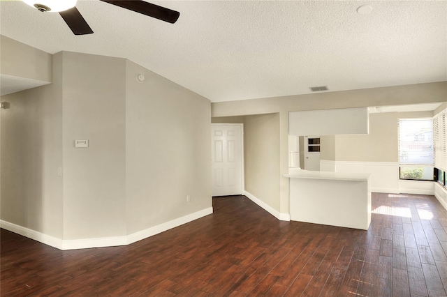 spare room with a textured ceiling, dark wood-type flooring, visible vents, and baseboards