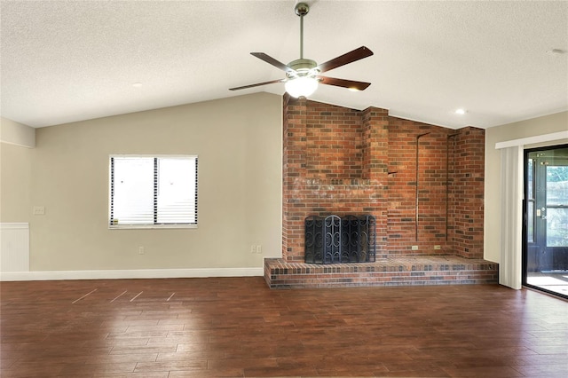 unfurnished living room with lofted ceiling, a brick fireplace, a textured ceiling, and dark wood-style flooring