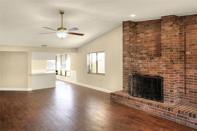 unfurnished living room featuring baseboards, dark wood finished floors, vaulted ceiling, a textured ceiling, and a fireplace