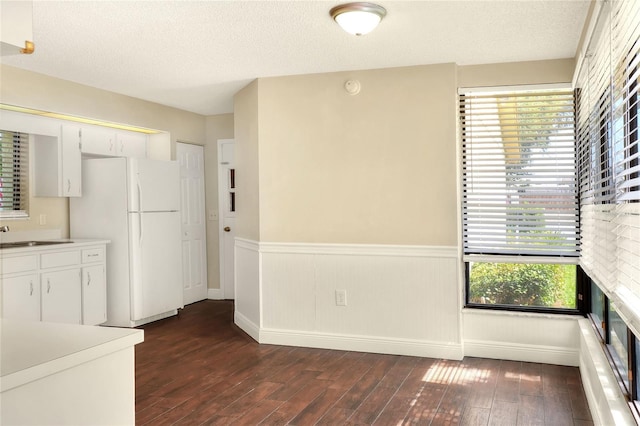 kitchen with dark wood-style floors, white cabinetry, light countertops, and freestanding refrigerator