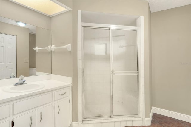 bathroom with a stall shower, vanity, baseboards, and tile patterned floors