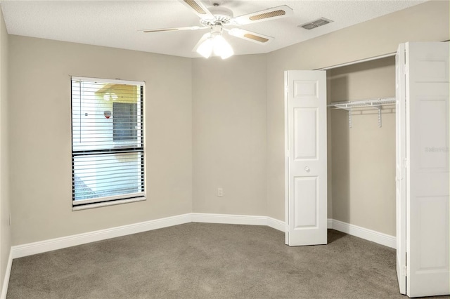 unfurnished bedroom with a textured ceiling, carpet floors, visible vents, baseboards, and a closet