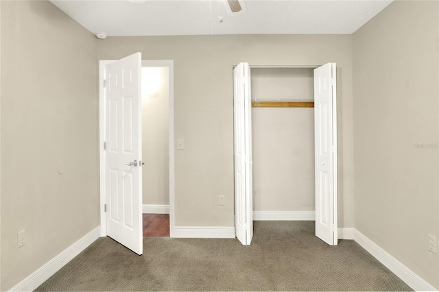 unfurnished bedroom featuring baseboards, dark carpet, ceiling fan, and a closet