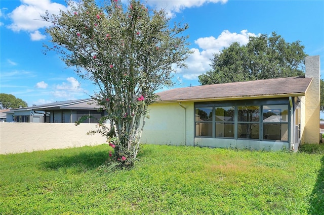 back of property with stucco siding, a chimney, fence, and a yard