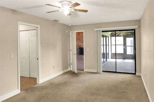 unfurnished room with visible vents, a ceiling fan, light carpet, a textured ceiling, and baseboards