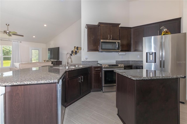 kitchen with ceiling fan, appliances with stainless steel finishes, dark stone countertops, and dark brown cabinetry