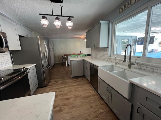 kitchen with tasteful backsplash, sink, stainless steel appliances, and gray cabinetry