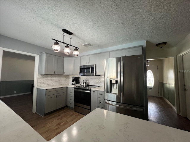 kitchen featuring dark wood-style floors, tasteful backsplash, appliances with stainless steel finishes, and gray cabinets