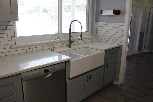 kitchen featuring backsplash, plenty of natural light, stainless steel dishwasher, and a sink