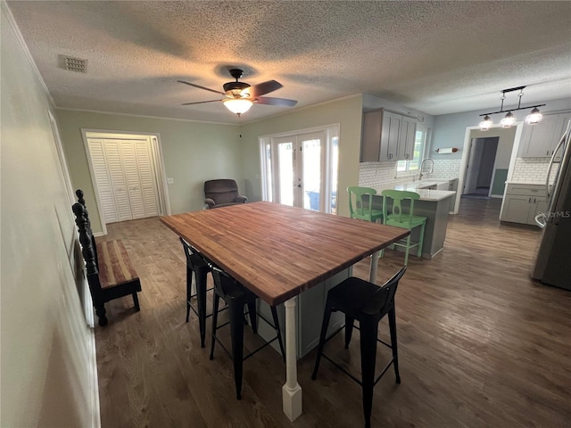 dining space featuring a textured ceiling, visible vents, french doors, and dark wood-type flooring