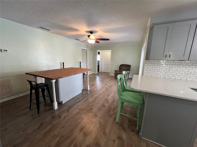 kitchen featuring baseboards, a breakfast bar area, visible vents, and tasteful backsplash