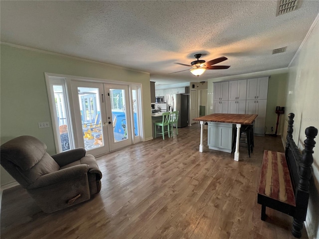 living room with hardwood / wood-style flooring, a textured ceiling, french doors, ceiling fan, and ornamental molding