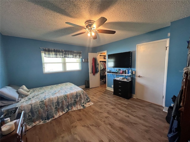 bedroom featuring hardwood / wood-style floors, ceiling fan, a spacious closet, and a closet