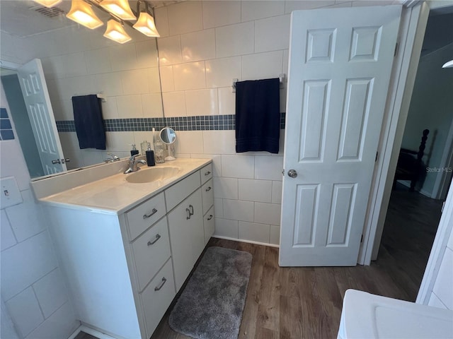 bathroom with tile walls, wood finished floors, and vanity