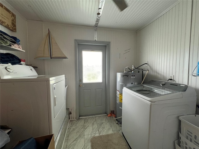 washroom featuring water heater, washer and clothes dryer, wooden walls, crown molding, and sink