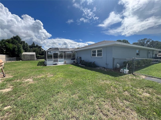 rear view of property with a yard, a lanai, and fence
