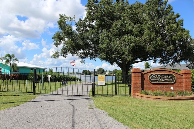 view of gate with fence and a lawn