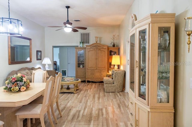 dining space with light hardwood / wood-style floors and ceiling fan with notable chandelier