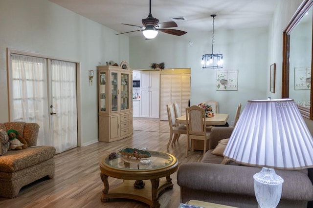 living room featuring light hardwood / wood-style flooring and ceiling fan with notable chandelier