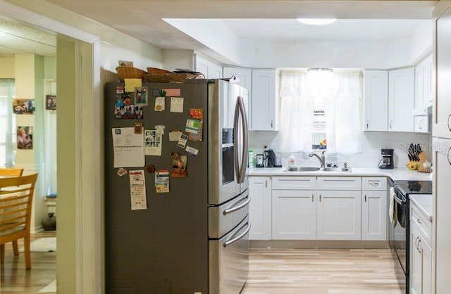 kitchen with white cabinets, range with electric stovetop, light hardwood / wood-style floors, sink, and stainless steel refrigerator with ice dispenser