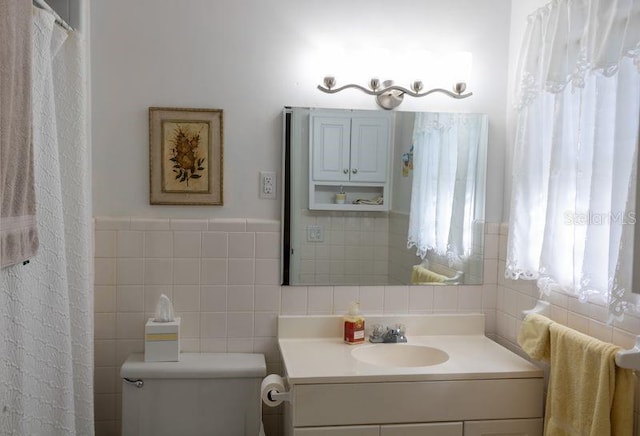 bathroom featuring vanity, toilet, and tile walls