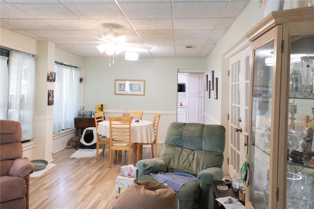 living room featuring ceiling fan, light hardwood / wood-style flooring, and a drop ceiling