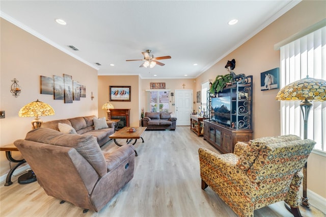 living area featuring ornamental molding, a wealth of natural light, visible vents, and wood finished floors