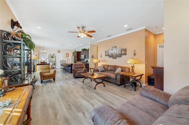 living area featuring recessed lighting, visible vents, light wood-style flooring, ornamental molding, and ceiling fan with notable chandelier