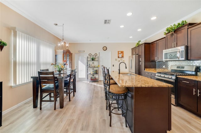 kitchen with stainless steel appliances, light hardwood / wood-style flooring, tasteful backsplash, and plenty of natural light