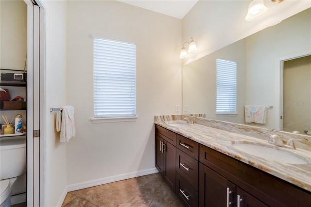 bathroom with plenty of natural light, tile patterned floors, toilet, and dual bowl vanity