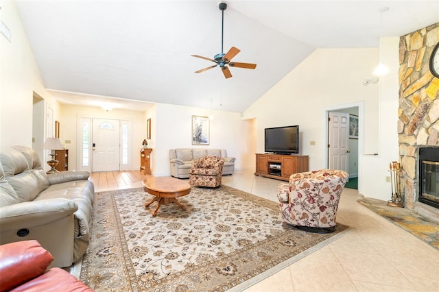 living room featuring light tile patterned floors, high vaulted ceiling, a ceiling fan, and a stone fireplace