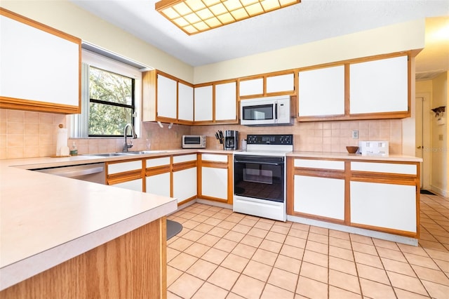 kitchen featuring light countertops, backsplash, white microwave, a sink, and range with electric cooktop