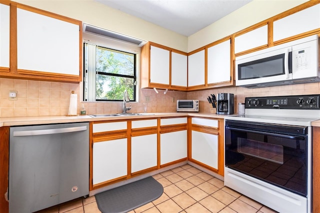 kitchen with range with electric stovetop, tasteful backsplash, stainless steel dishwasher, white microwave, and a sink