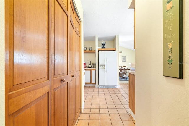 corridor featuring vaulted ceiling and light tile patterned floors