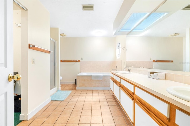 full bath featuring a skylight, a sink, visible vents, a shower stall, and tile patterned floors