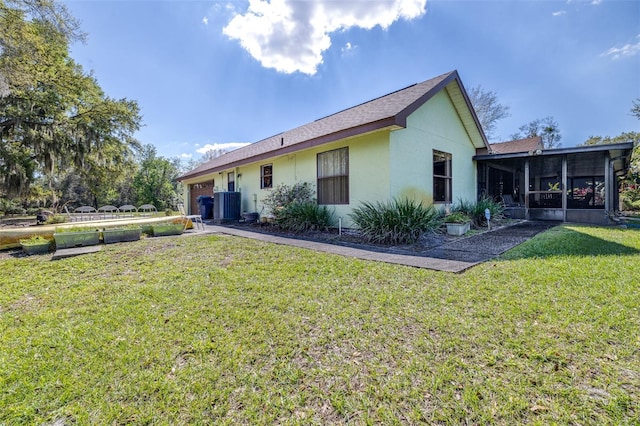 rear view of property with an attached garage, cooling unit, a sunroom, a yard, and stucco siding