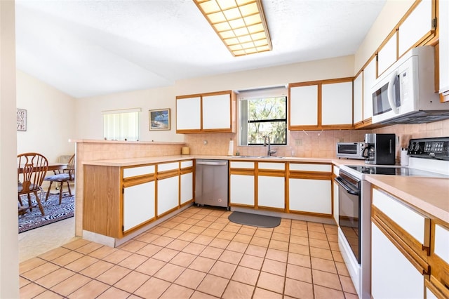 kitchen featuring range with electric cooktop, white microwave, light countertops, white cabinetry, and stainless steel dishwasher