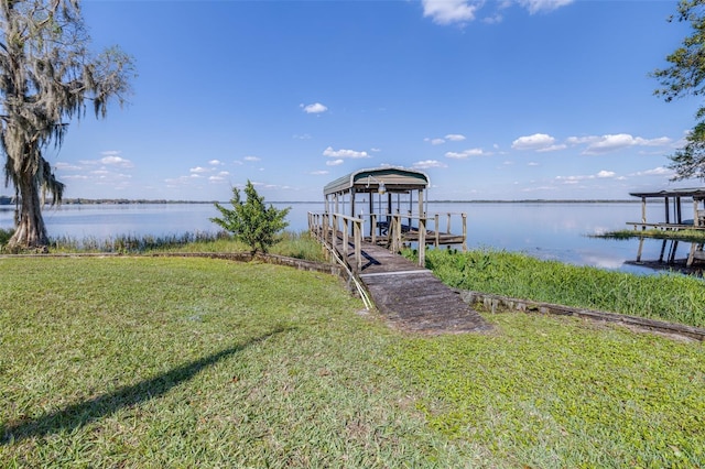 dock area with a water view and a lawn