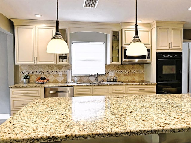 kitchen featuring light stone countertops, sink, tasteful backsplash, cream cabinetry, and black appliances