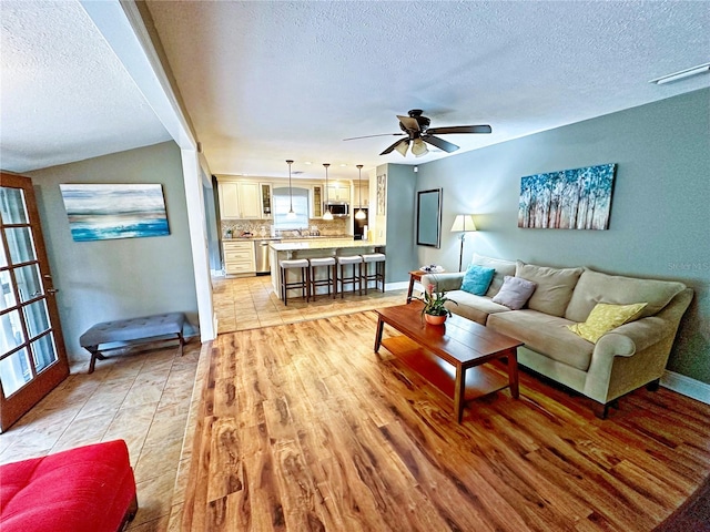 living room featuring light tile patterned flooring, a textured ceiling, and ceiling fan