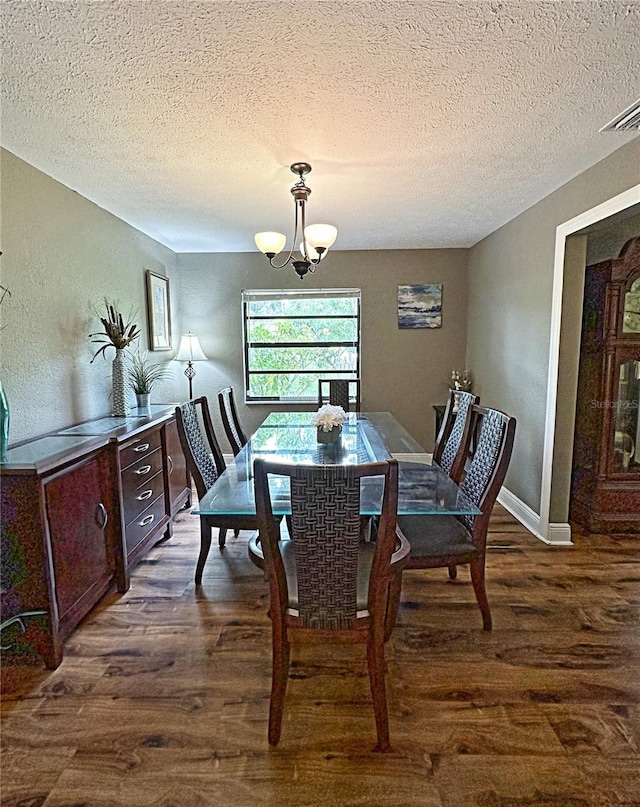 dining area with wood-type flooring, a textured ceiling, and an inviting chandelier