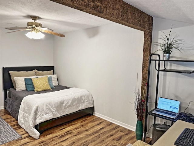 bedroom with ceiling fan, a textured ceiling, and hardwood / wood-style flooring