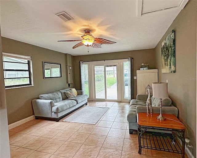 living room with ceiling fan, light tile patterned flooring, and a textured ceiling