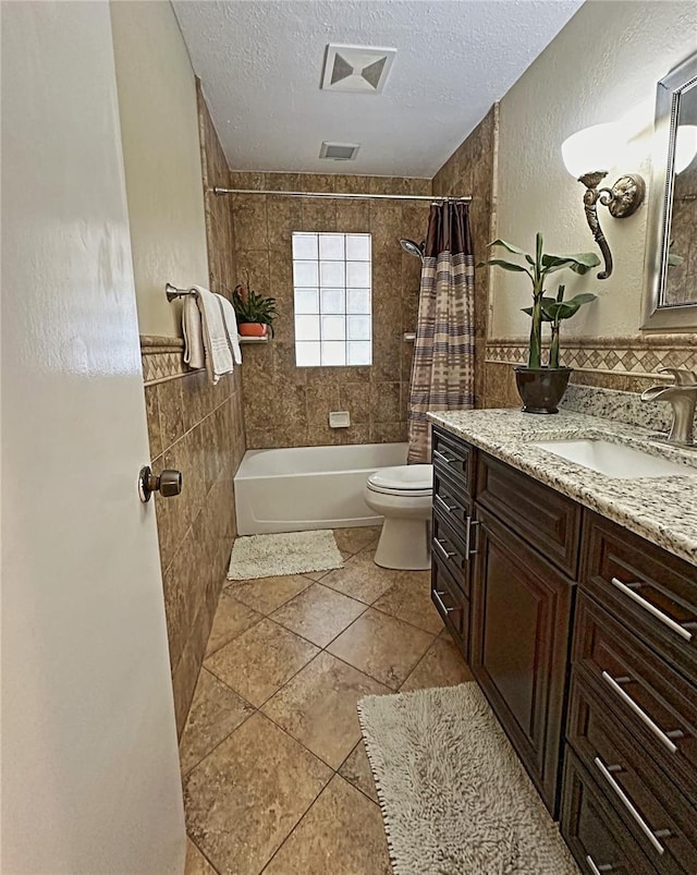 full bathroom with a textured ceiling, toilet, tile patterned floors, shower / bath combination with curtain, and vanity