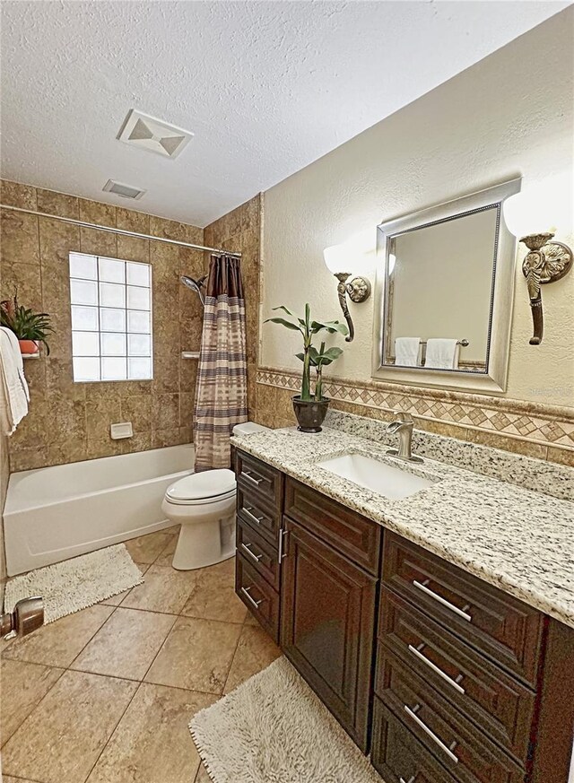 full bathroom featuring a textured ceiling, toilet, shower / tub combo with curtain, tile patterned floors, and vanity